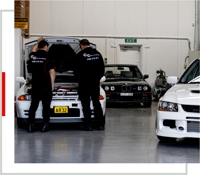 Two men working on a car in a garage.