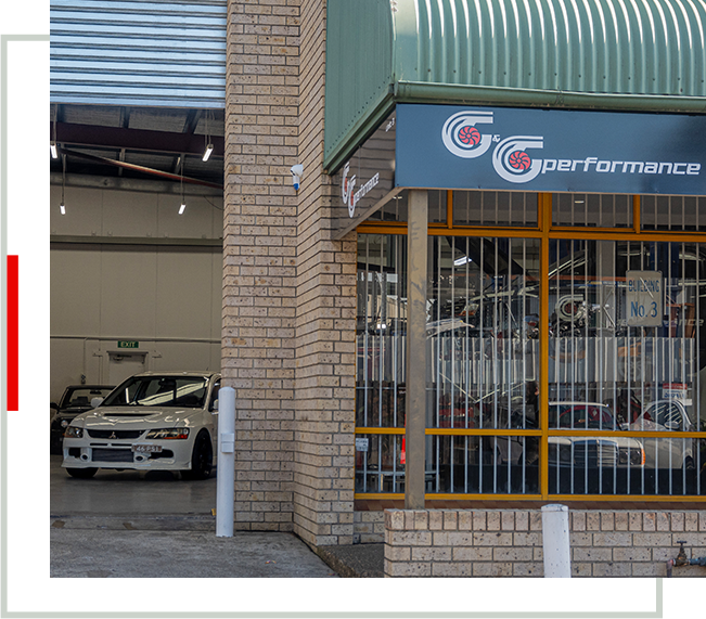 A car dealership with two cars parked in front of it.